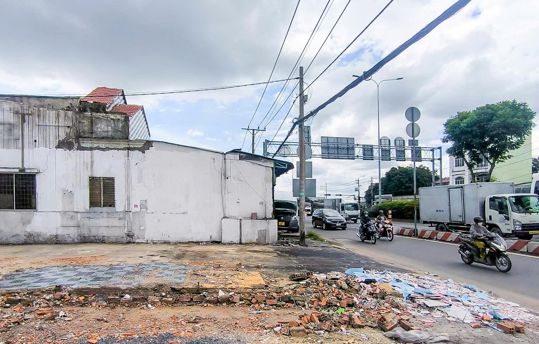 Mặt bằng đã tháo dỡ dọc Quốc lộ 22, chỉ còn trơ nền nhà, phía sau là dòng xe đang chạy